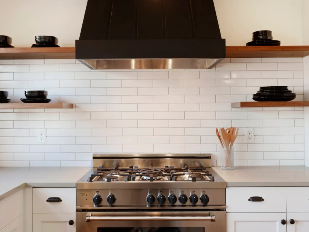 kitchen with white subway tiles silver stove and dark hood
